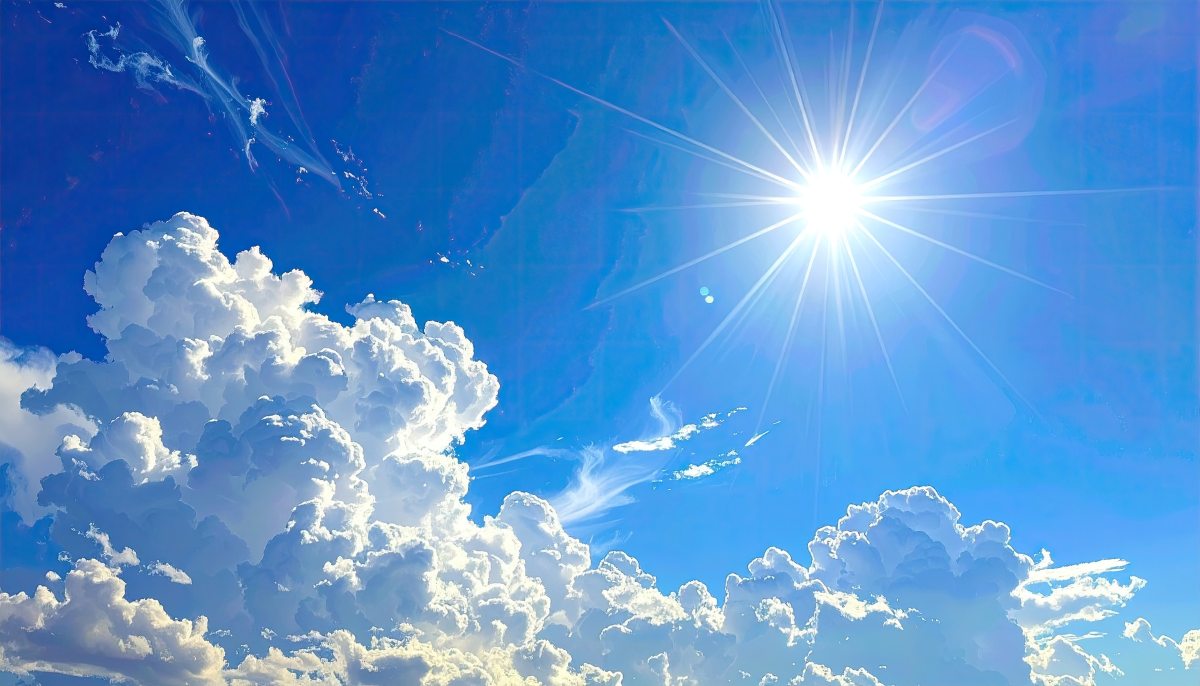 Bright sun shines through puffy white clouds against a vibrant blue sky